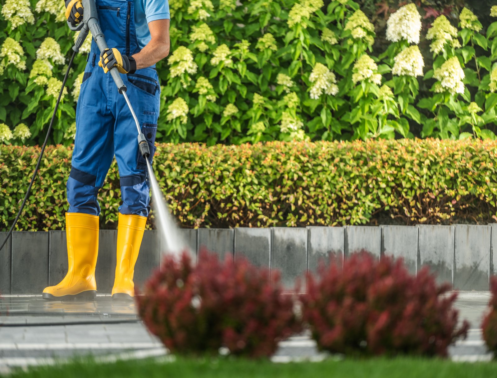 Caucasian Man Pressure Washing Elegant Driveway Using Modern Pressure Washer