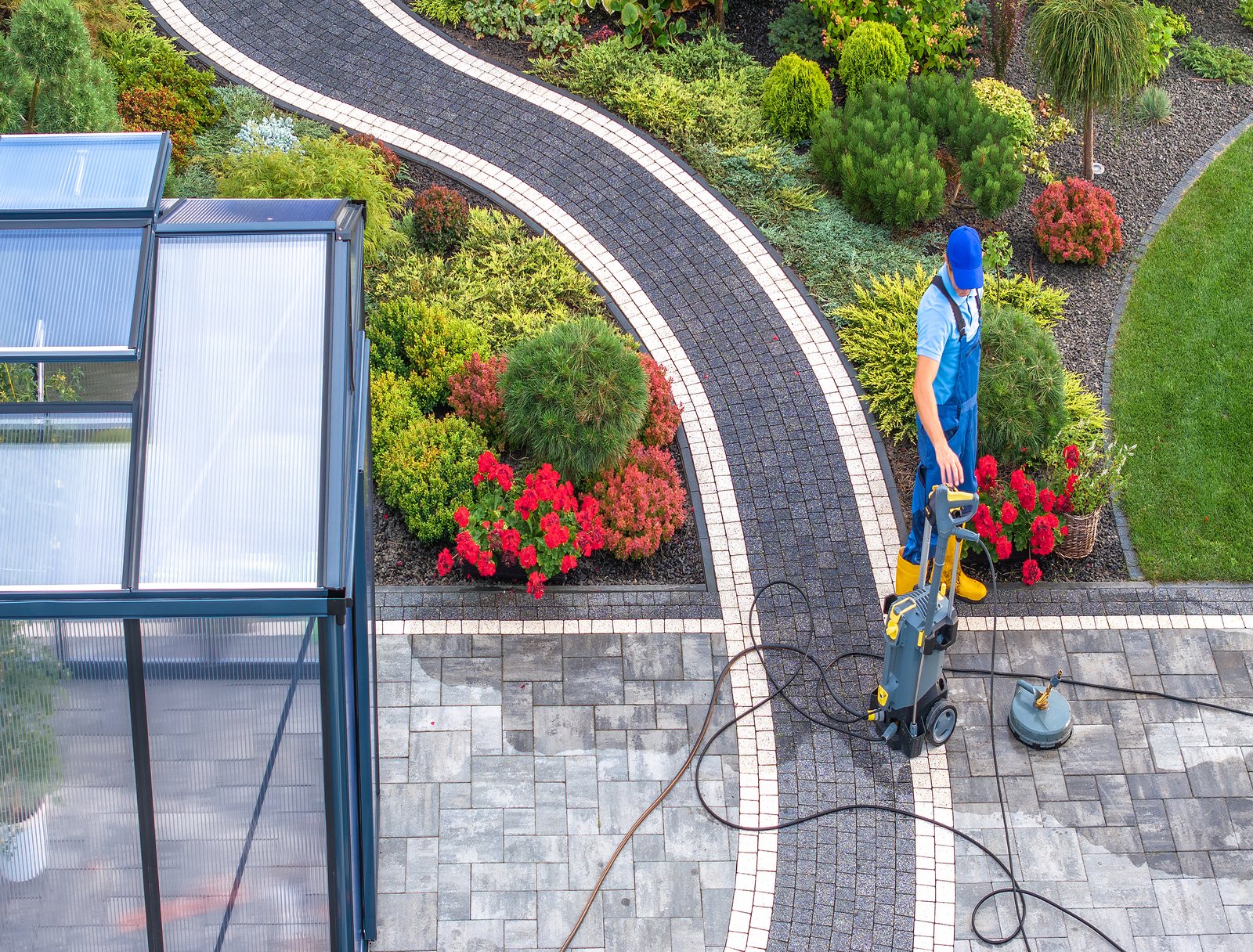 Caucasian Man in His 40s Cleaning His Backyard Garden Paths Using Pressure Washer Aerial View